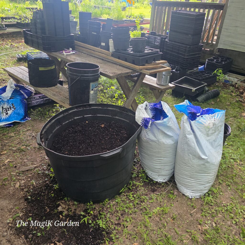 Giant tree pot full of used soil and a stack of emptied pots on top of an old picnic table